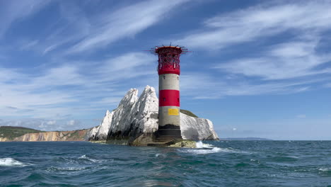 Landscape-shot-from-boat-showing-a-lighthouse-on-the-shore-line-of-the-Isle-of-Wight-next-the-the-famous-Needles-cliffs