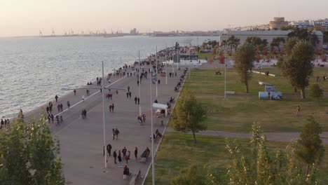 Antenne---Gehweg-Am-Meer-Von-Thessaloniki-Mit-Menschen,-Die-In-Der-Abenddämmerung-Spazieren-Gehen