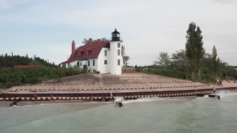 Historic-Point-Betsie-Lighthouse-in-Frankfort,-Michigan-located-along-Lake-Michigan-with-drone-video-low-on-water-moving-in
