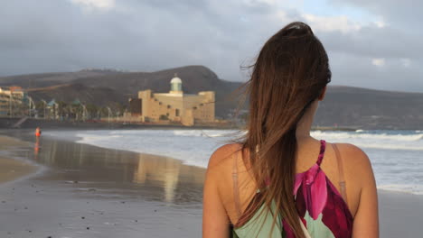 Cinematic-shot-of-a-woman-admiring-the-Alfredo-Kraus-auditorium-from-Las-Canteras-beach,-on-the-island-of-Gran-Canaria
