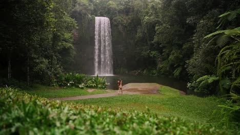 Female-walks-in-bikini-towards-beautiful-secluded-waterfall-in-tropical-rainforest