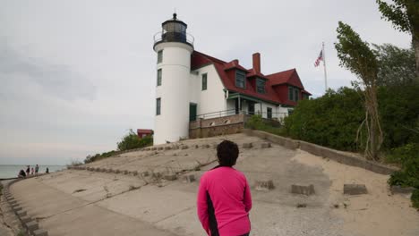 Woman-walking-near-historic-Point-Betsie-Lighthouse-in-Frankfort,-Michigan-along-Lake-Michigan-with-gimbal-video-from-behind-in-slow-motion