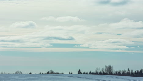 Static-shot-of-snowmobile-passing-by-in-timelapse-over-cold-winter-rural-landscape-on-a-cloudy-day