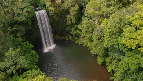 Top-down-drone-shot,-with-slow-cinematic-pan-into-beautiful-secluded-waterfall-in-tropical-rainforest