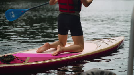 Woman's-knees-as-she-begins-paddling-away-on-a-paddle-board