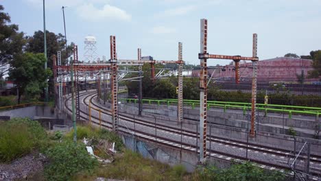Car-passing-next-to-neglected-urban-train-tracks,-a-water-tank-can-be-seen-in-the-background