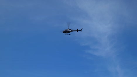 Helicóptero-Negro-Pasando-Visto-Desde-El-Suelo,-Tiro-De-Seguimiento-De-Dolly
