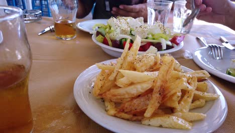 Close-up-Shot-Of-A-Feta-Salad-And-A-Plate-Of-Chips-Being-Dished-Out-Onto-A-Plate-In-A-Restaurant