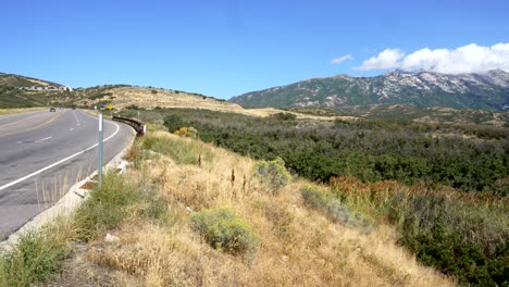 Panning-view-of-the-Rocky-Mountains-and-a-winding-road-hear-Highland,-Utah-in-summer
