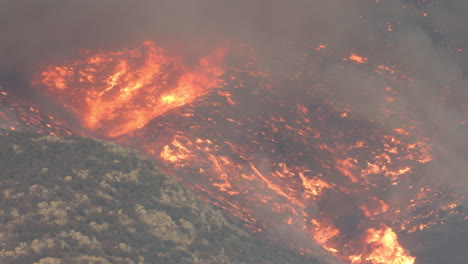 Aerial-view-of-burning-mountain-forestry-with-heavy-blazing-orange-flames-and-smog-in-Hemet,-California---6-September-2022