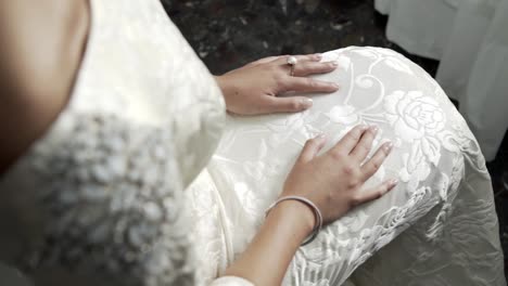 Braut-Mit-Ihren-Händen-Auf-Den-Knien,-Das-Hochzeitskleid-Anziehen
