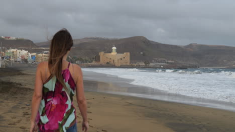 Fantastic-cinematic-shot-at-dawn-of-a-woman-walking-on-the-beach-of-Las-Canteras-and-in-the-background-you-can-see-the-Alfredo-Kraus-Auditorium