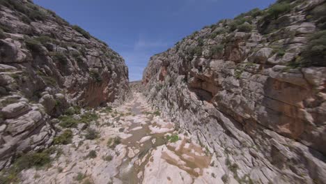 Dramatic-FPV-aerial-flight-in-arid,-rugged,-narrow-rock-river-canyon