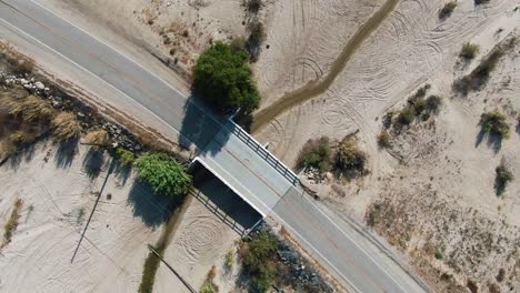 A-bridge-over-a-dry-river,-drying-river-bed-aerial
