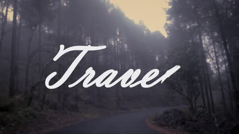 The-word-"travel"-written-in-white-on-a-path-between-trees-covered-in-fog