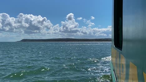 Glitzerndes-Meer-Und-Blauer-Himmel-Mit-Flauschigen-Weißen-Wolken-Von-Einem-Boot,-Das-Auf-Eine-Idyllische-Und-Ruhige-Pazifische-Insel-Vor-Der-Küste-Australiens-Zusteuert