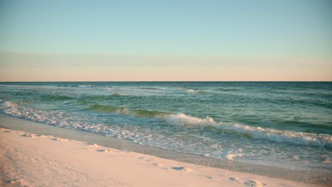Shots-of-the-ocean-on-a-warm,-sunny-evening-with-footprints-in-the-sand