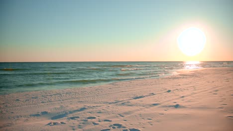 Shots-of-the-ocean-on-a-warm,-sunny-evening-with-footprints-in-the-sand-facing-the-sun-directly-2
