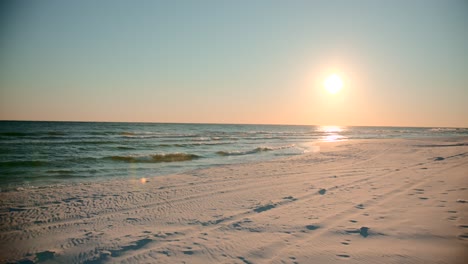 Shots-of-the-ocean-on-a-warm,-sunny-evening-with-footprints-in-the-sand-facing-the-sun-directly-1
