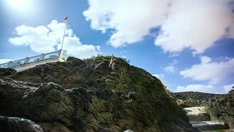 Hyper-lapse-of-the-ascent-of-a-camera-through-some-rocks-to-a-flag-on-the-coast-of-Guernsey
