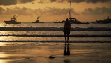 Beach-silhouette-of-someone-walking-over-the-beach-with-her-feet-in-the-ocean-of-Playa-Tamarindo,-Costa-Rica