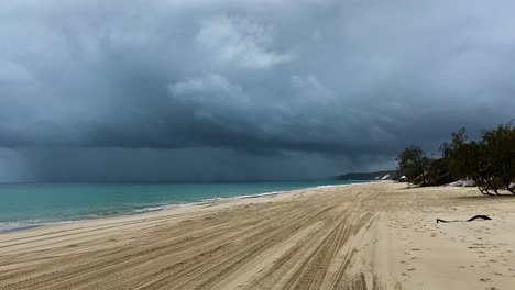 Layers-and-contrasts---4x4-tracks-on-the-beach-reach-into-the-distance-as-a-dark-and-angry-storm-hangs-over-the-green-Pacific-Ocean