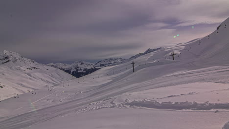 Thick-fresh-snow-on-slope-at-ski-resort-with-chair-lift---clouds-moving-over-white-winter-landscape