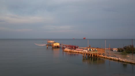 Luftaufnahme-Von-Fischerhütten-Am-Ufer-Der-Mündung-Bei-Sonnenuntergang,-Italienische-Fischermaschine,-Genannt-&quot-1