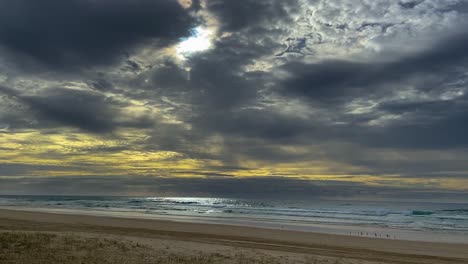 Storm-clouds-gather-at-dawn-over-the-Pacific-Ocean,-while-the-sun-attempts-to-break-through-the-clouds