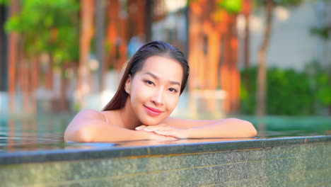 Close-up-of-a-pretty-young-woman-leaning-along-the-edge-of-an-infinity-pool-as-water-drips-over-the-edge