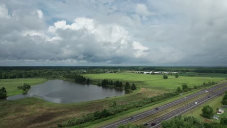 Drone-capture-the-busy-highway-where-numerous-car-speeding-with-the-beautiful-still-lake