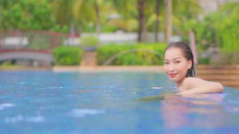 Eine-Schöne,-Sexy-Frau-Richtet-Ihren-Blick-Auf-Die-Kamera,-Während-Sie-Sich-Im-Wasser-Eines-Noblen-Tropischen-Resorts-Entspannt