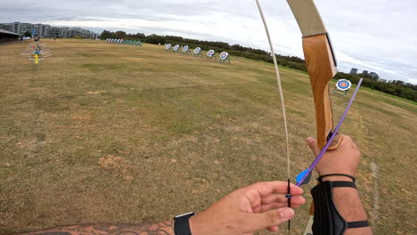 POV-An-archer-nocks-an-arrow-to-his-bow-and-shoots-it-at-an-archery-target