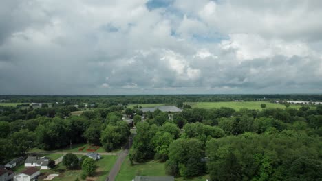 On-a-cloudy-day,-a-drone-captures-the-town-from-a-great-height,-surrounded-by-tall-trees