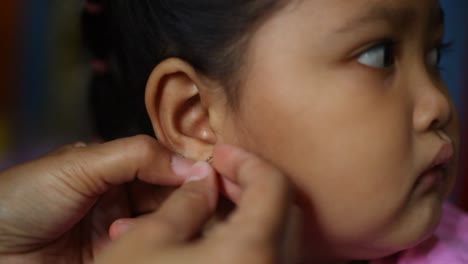 Close-up-Asian-Mom's-hand-put-on-earings-to-her-daughter
