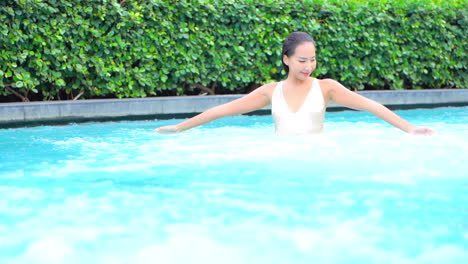 An-attractive-woman-walks-through-the-bubbles-and-foam-in-a-resort-swimming-pool