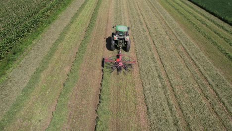 On-a-farm-field-in-southwest-Wisconsin,-a-farmer-rakes-hay-using-a-rotary-hay-rake-2