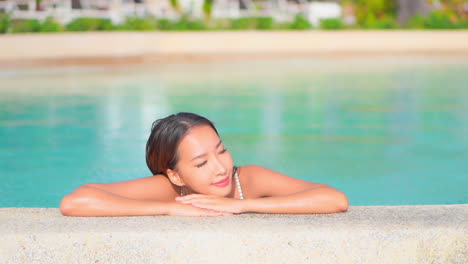 AA-pretty-woman,-while-chilling-in-a-swimming-pool,-lies-her-head-down-on-her-hands,-daydreaming-about-her-perfect-vacation