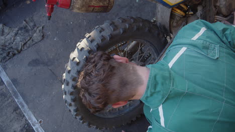 Bike-mechanic-checking-or-repairing-brake-system-of-motorbike-at-garage