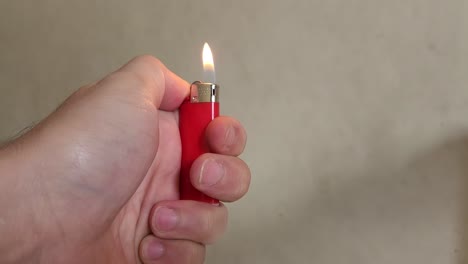 Video-of-a-hand-lighting-a-small-red-lighter-and-then-letting-the-flame-go-out