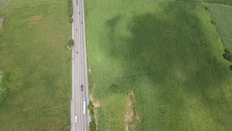 Luftaufnahme-Einer-Wenig-Befahrenen-Straße-Mit-Getreidefeldern-Auf-Beiden-Seiten-Und-Wolkenschatten-Auf-Dem-Boden