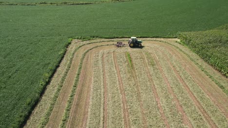 On-a-farm-field-in-southwest-Wisconsin,-a-farmer-rakes-hay-using-a-rotary-hay-rake-1