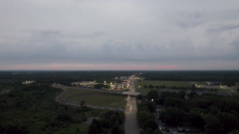 Aerial-drone-shot-over-a-highway-with-narrows-lanes-with-small-homes-on-both-sides-of-a-road-at-sunset