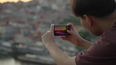 A-tourist-in-the-city-of-Porto-taking-a-picture-of-the-sunset-in-public
