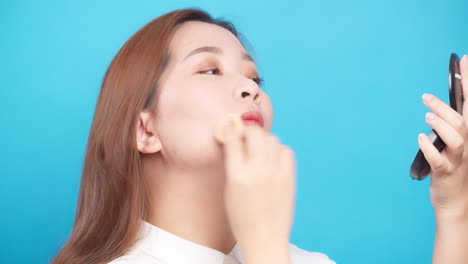 Close-Up-of-Asian-woman-applying-powder-face-for-wellness-skin-care-on-blue-background-1