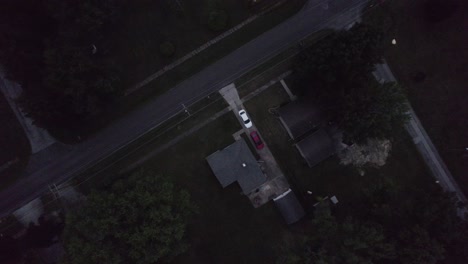 Aerial-drone-bird's-eye-view-over-cars-parked-infront-of-a-small-town-home-during-evening-time