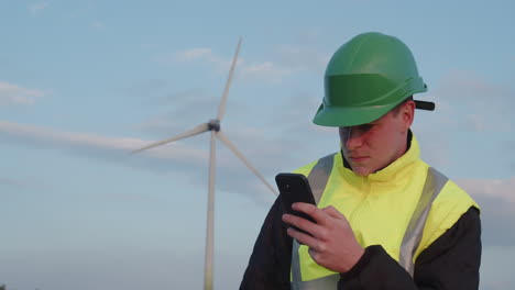 Young-engineer-checks-wind-turbine-performance-data-on-his-mobile-phone