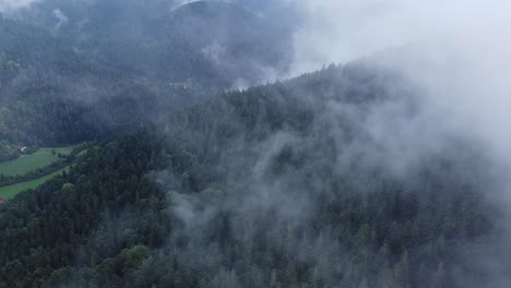 Vista-Aérea-De-Un-Oscuro-Bosque-De-Montaña-Con-Grandes-Nubes-Blancas-Malhumoradas,-En-Vosges,-Francia,-4k
