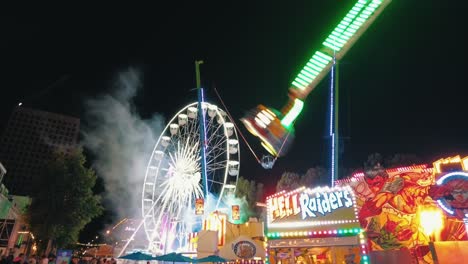 Thrilling-ferris-wheel,-swing,-free-fall-attractions-funfair-Tilburg-nighttime