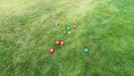 High-angle-shot-of-playing-traditional-boules-game-throwing-heavy-shiny-red-and-green-balls-at-target-at-daytime